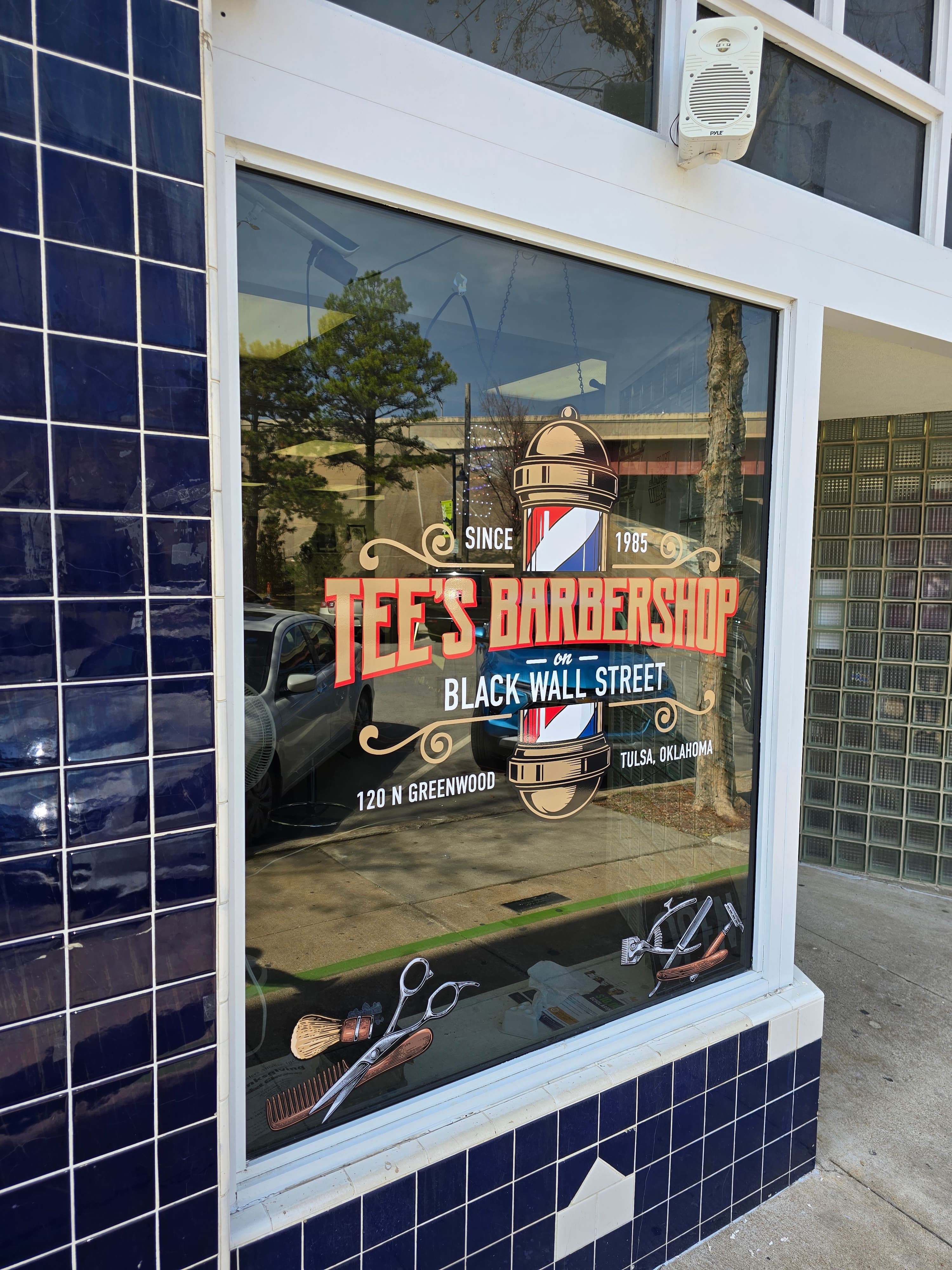 Tee's Barbershop storefront window on Black Wall Street in Tulsa, Oklahoma, with vintage signage.