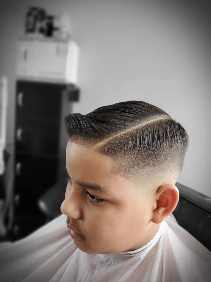 Young boy with a sharp side part, slicked-back hair, and a clean skin fade.